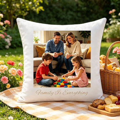 Custom family photo pillow placed on a checkered picnic blanket in a blooming garden, next to a wicker basket of snacks. A joyful, summery touch showing the pillow as part of outdoor family gatherings.
