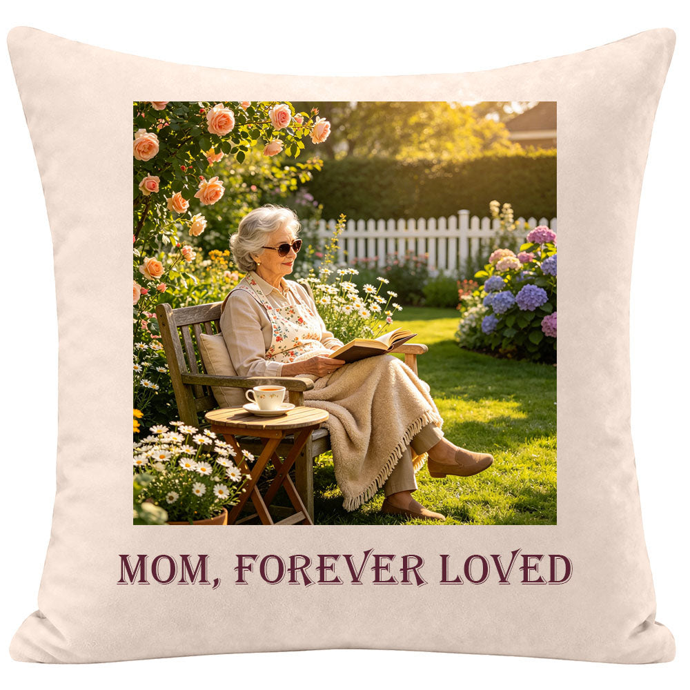 Personalized memorial throw pillow with a photo of an elderly woman reading in a sunny flower garden, engraved with "Mom, Forever Loved", keepsake gift for remembering a mother or grandmother, soft cream fabric sympathy pillow