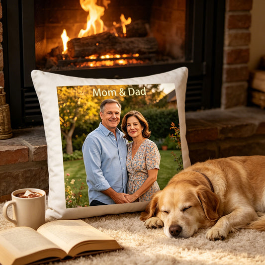 Custom Mom & Dad keepsake pillow resting on a cozy rug in front of a lit fireplace, with a sleeping golden retriever and open book nearby. A warm, nostalgic scene showing the pillow as a reminder of family love in a daughter’s home.