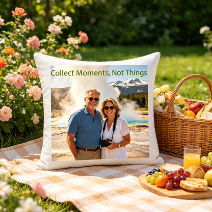 Custom travel keepsake pillow resting on a checkered picnic blanket in a blooming garden, with a wicker basket of fruit and bread nearby. A cheerful, summery touch showing the pillow as part of relaxed, nature-filled moments.